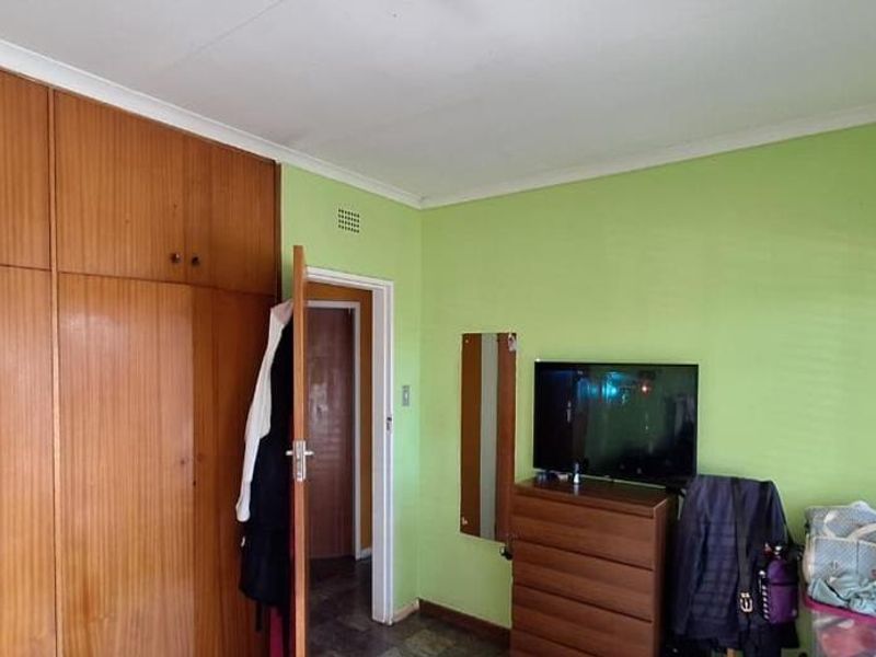 A bedroom featuring floor-to-ceiling built-in wooden cupboards and venetian blinds, offering functional storage space.