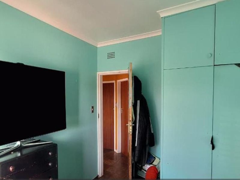 A bedroom featuring built-in cupboards and painted walls, offering a functional space with potential for cosmetic updates to modernize the interior finishes.