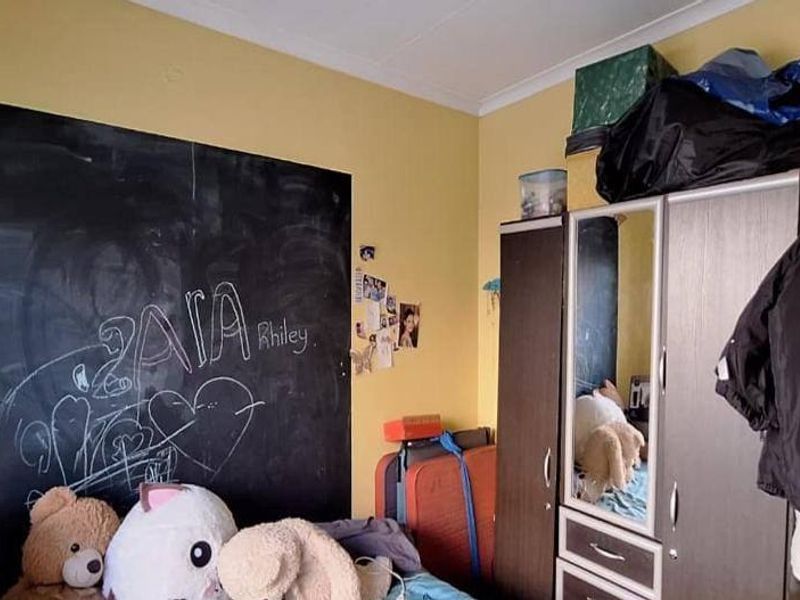 A bedroom featuring a built-in wardrobe and a wall finished with chalkboard paint, requiring cosmetic updates to improve the overall aesthetic.