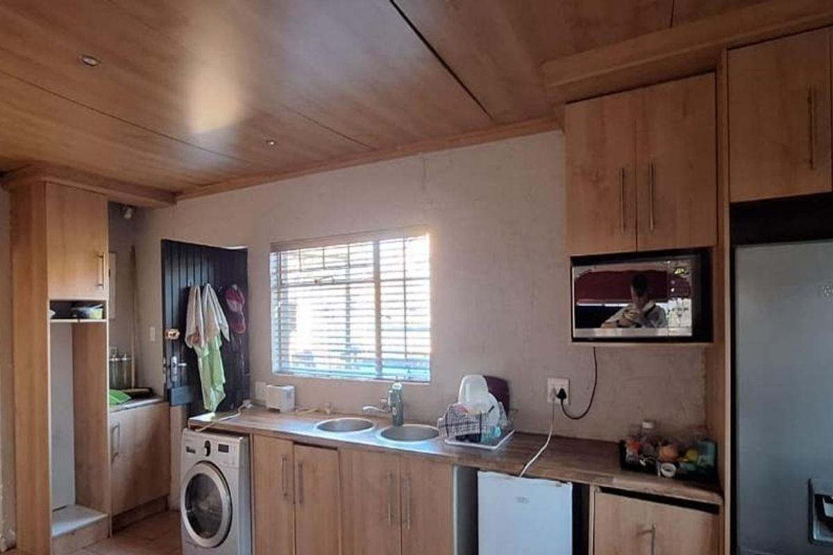 A functional kitchen featuring light wood-look cabinetry, a double bowl sink, and integrated microwave space with recessed ceiling lighting.