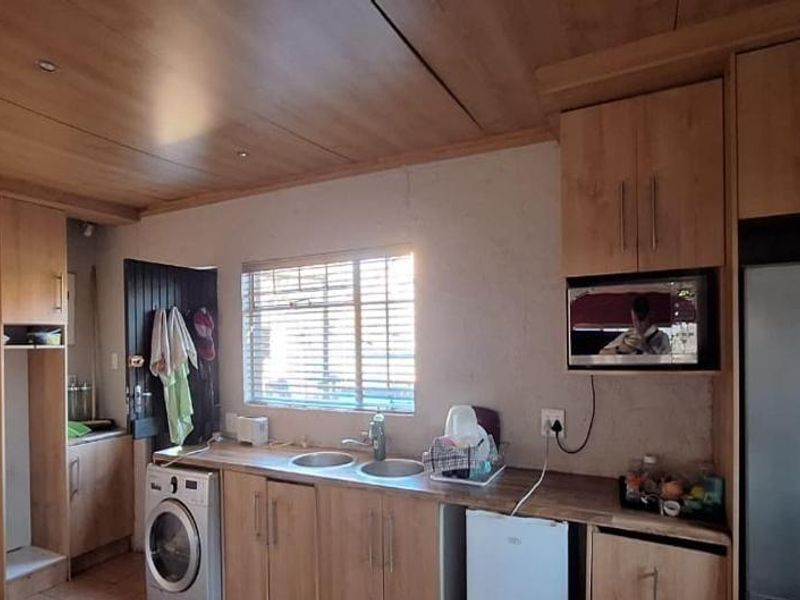 A functional kitchen featuring light wood-look cabinetry, a double bowl sink, and integrated microwave space with recessed ceiling lighting.