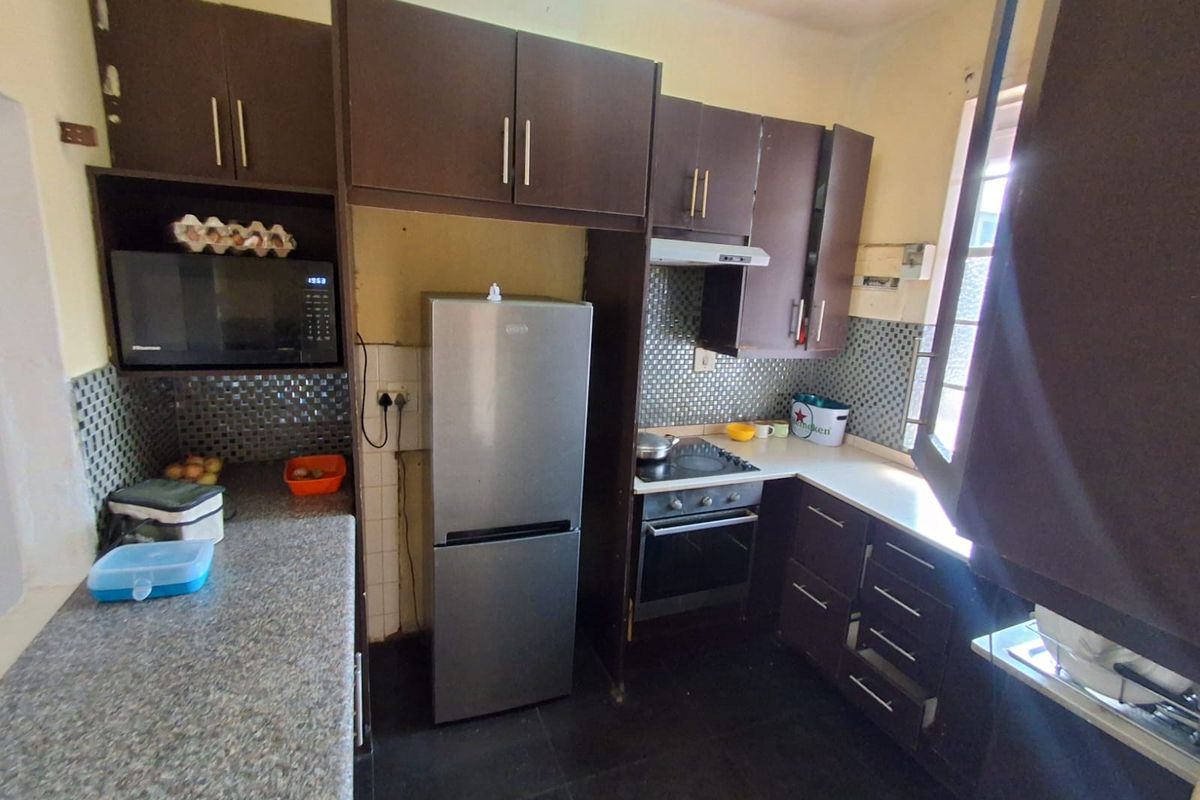 A functional kitchen featuring dark cabinetry, mosaic tile backsplash, built-in oven, hob, and extractor fan, offering a practical layout for daily meal preparation.