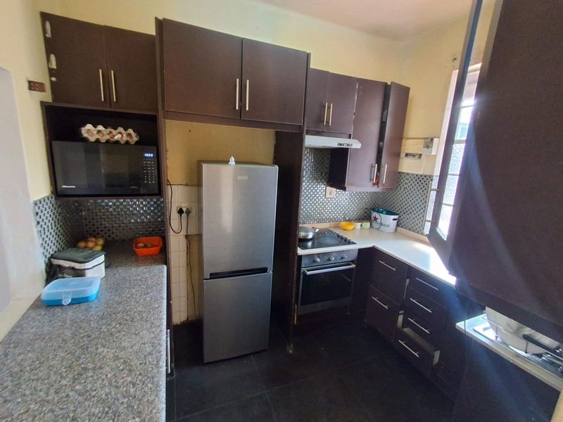 A functional kitchen featuring dark cabinetry, mosaic tile backsplash, built-in oven, hob, and extractor fan, offering a practical layout for daily meal preparation.