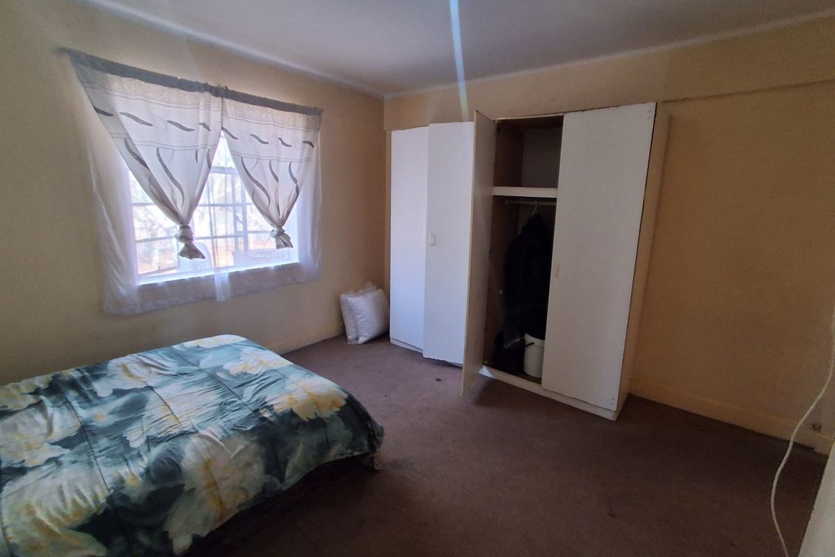 A bedroom featuring built-in wardrobe storage and carpeted flooring, offering a functional space with potential for cosmetic updates.