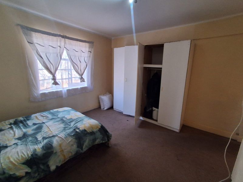 A bedroom featuring built-in wardrobe storage and carpeted flooring, offering a functional space with potential for cosmetic updates.