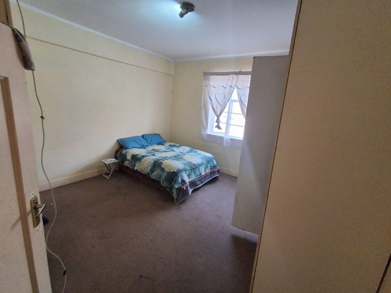 A simple bedroom featuring carpeted flooring and a ceiling light fixture, offering a blank canvas for potential updates and modernization.