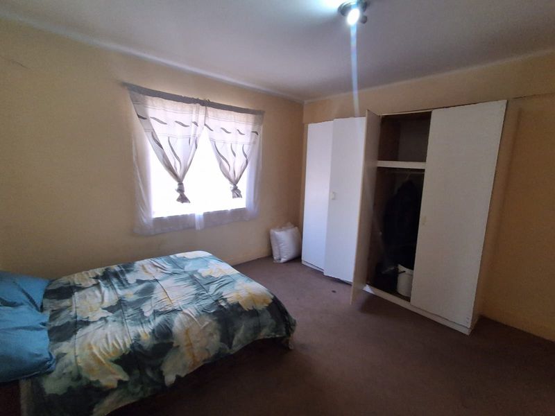A bedroom featuring built-in cupboards and carpeted flooring, offering a functional space with potential for cosmetic updates.