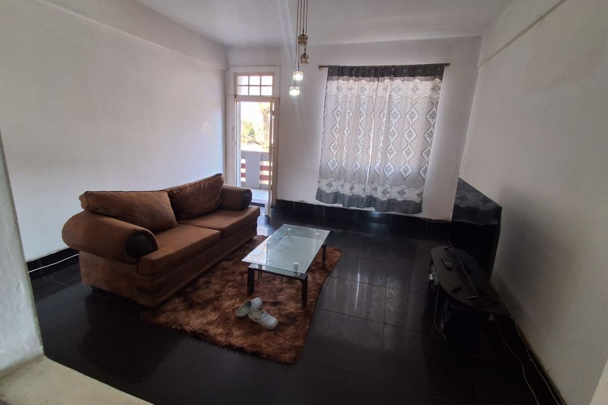 A living room featuring dark tiled flooring, pendant lighting, and direct access to an outdoor balcony area.