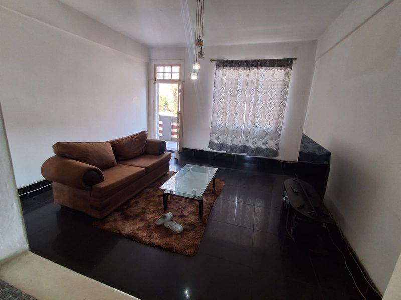 A living room featuring dark tiled flooring, pendant lighting, and direct access to an outdoor balcony area.