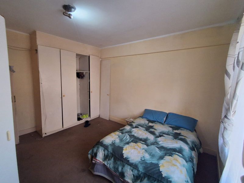 A bedroom featuring built-in wardrobes and carpet flooring, requiring cosmetic updates to improve the overall condition and appeal of the space.