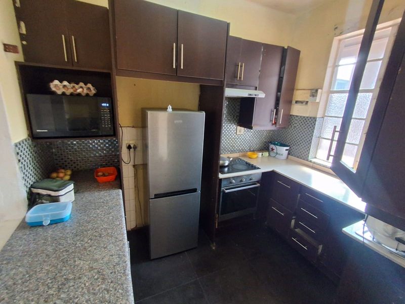 Compact kitchen featuring dark cabinetry, mosaic tile backsplash, and built-in appliances, offering a functional layout with potential for cosmetic updates.