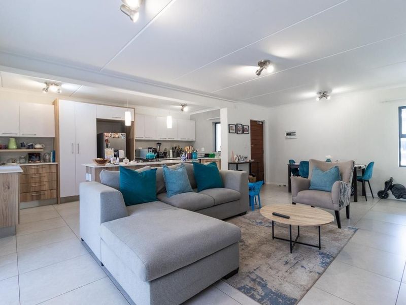 Spacious open-plan living area featuring a modern kitchen with built-in cabinetry, a central island, and neutral tiled flooring throughout.