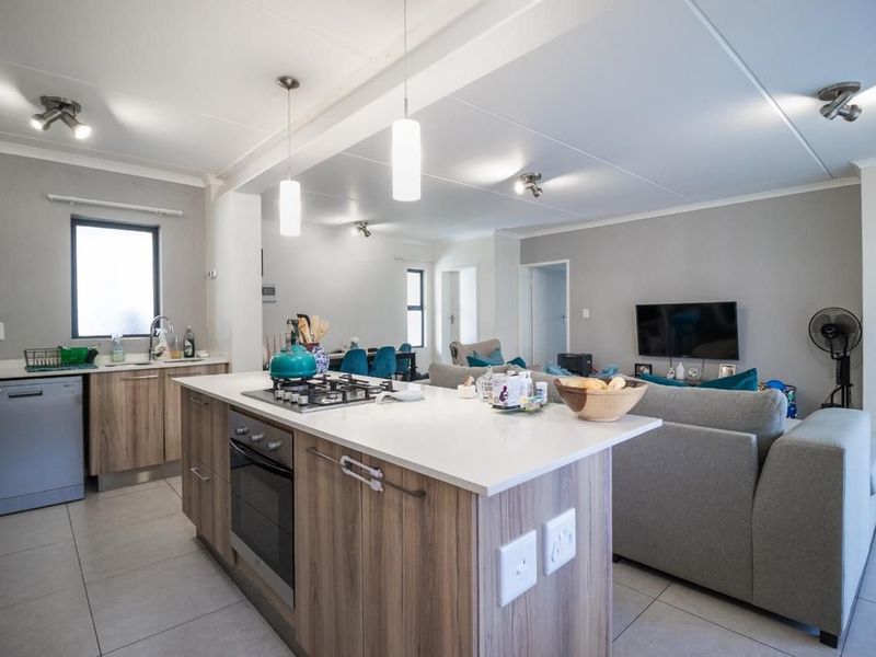 Modern open-plan living area featuring a contemporary kitchen with a central island, gas hob, built-in oven, and seamless flow into the lounge space.