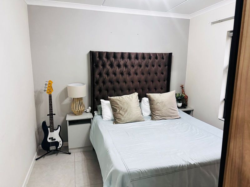 A well-maintained bedroom featuring neutral wall tones, tiled flooring, and decorative coving, providing a clean and functional living space.