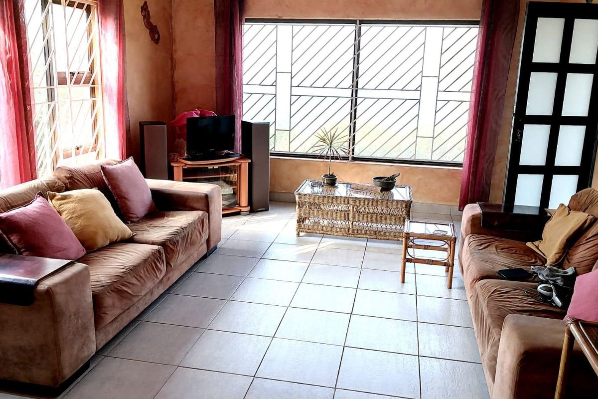 A living room featuring tiled flooring and large windows with security bars, providing natural light to the space.