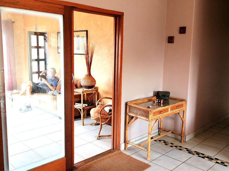 A tiled hallway featuring a sliding glass door leading to an adjacent living space, with a decorative floor border and neutral wall finishes.