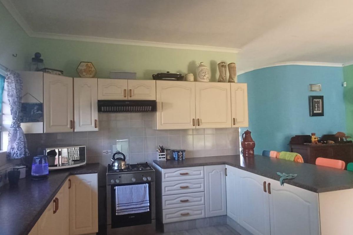 A functional kitchen featuring built-in cabinetry, laminate countertops, a gas stove with extractor fan, and a convenient breakfast bar area.