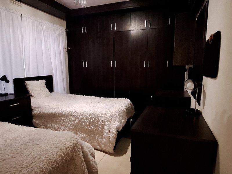 A bedroom featuring dark wood built-in cupboards and tiled flooring, providing functional storage space.