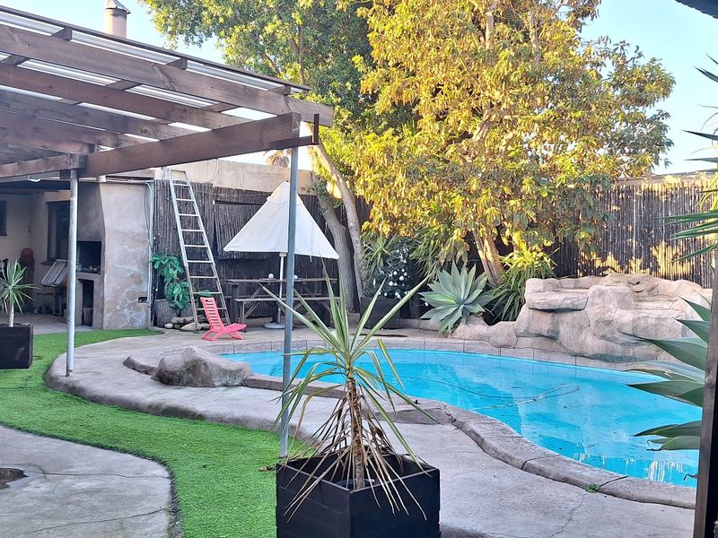 Outdoor entertainment area featuring a swimming pool, rock water feature, and a timber pergola, providing a relaxed space for leisure and social gatherings.