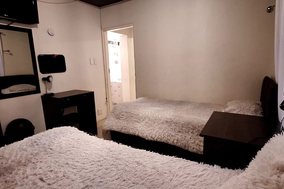 A bedroom featuring neutral walls, built-in shelving, and a doorway leading to an adjacent room.