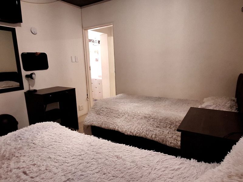 A bedroom featuring neutral walls, built-in shelving, and a doorway leading to an adjacent room.