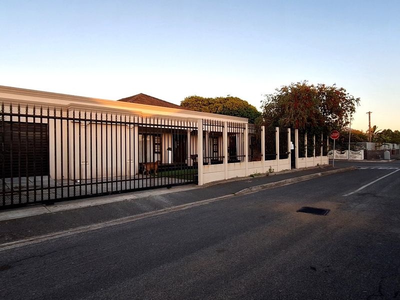 Front exterior view of the property featuring a secure wrought iron fence, sliding gate, and concrete boundary wall along the street.