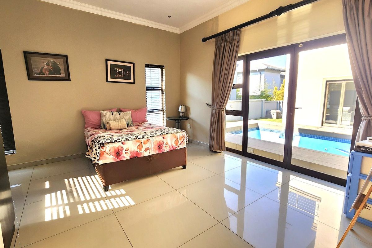 Spacious bedroom featuring large sliding glass doors that open directly onto a private pool area, complemented by neutral tiled flooring and modern finishes.