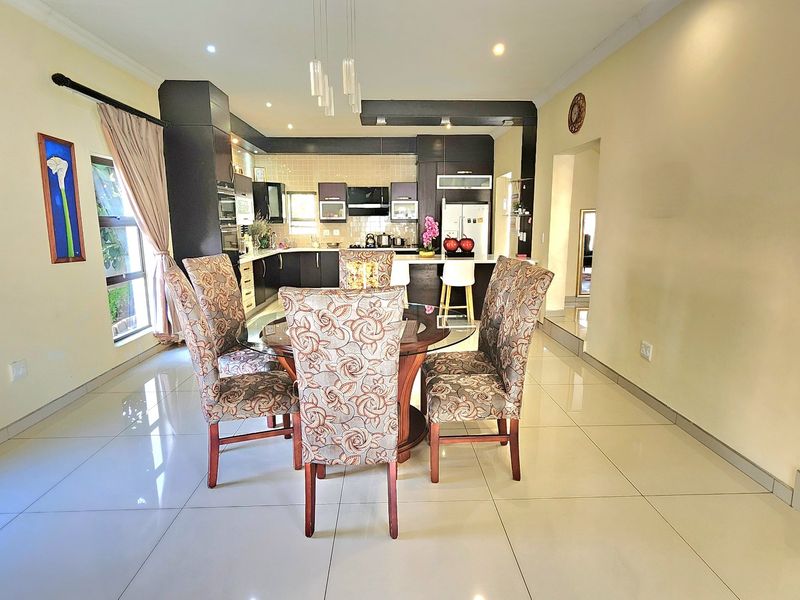 Open-plan living and dining area featuring a modern kitchen with dark cabinetry, a central island, and sleek tiled flooring throughout.