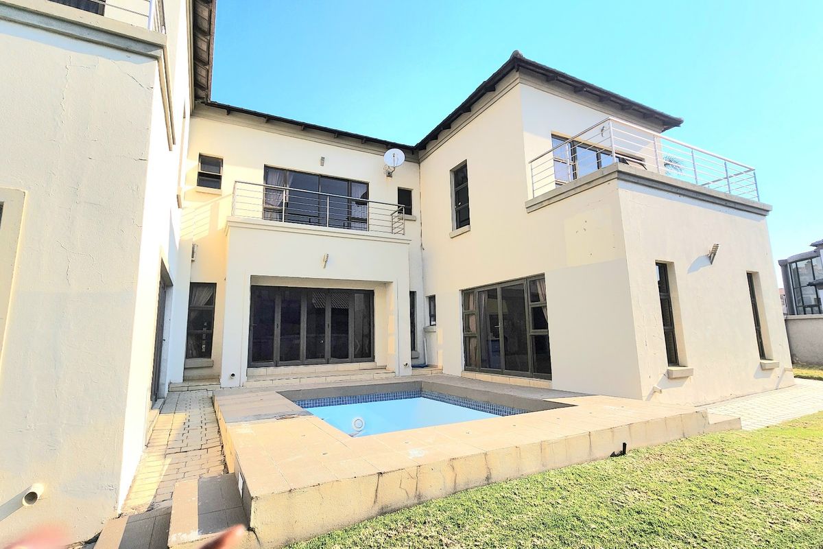 Rear view of the property featuring a swimming pool, paved patio area, and upper-level balconies with stainless steel railings.