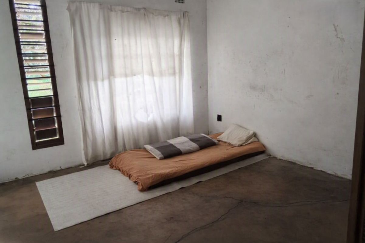 A basic bedroom featuring a concrete floor with visible cracking and plain walls requiring maintenance or cosmetic updates.