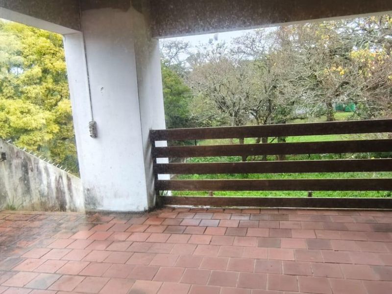 A covered outdoor patio area featuring tiled flooring, a timber balustrade, and views of the surrounding garden.