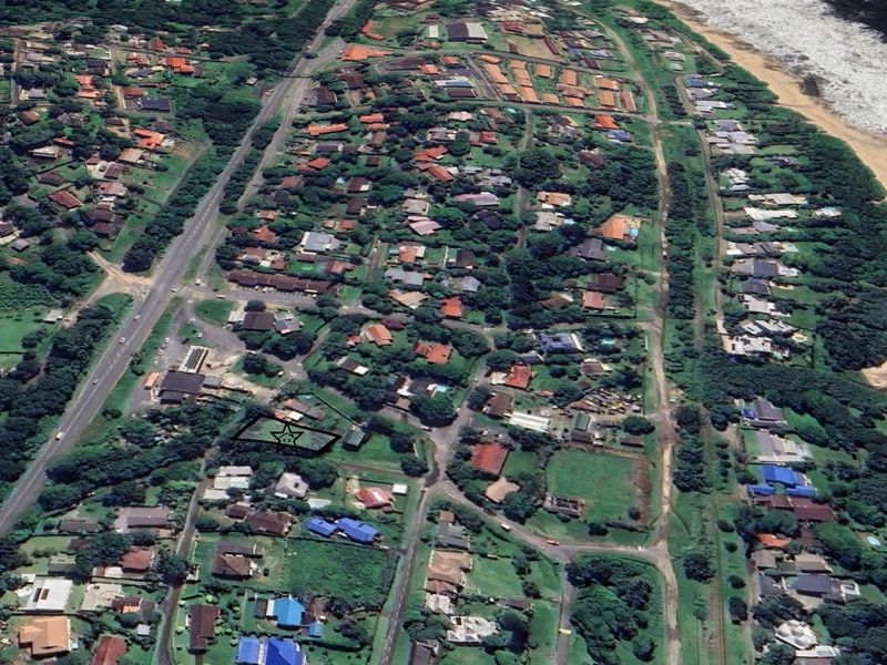 An aerial view of a residential neighborhood situated along the coastline, highlighting the property's location within the community.