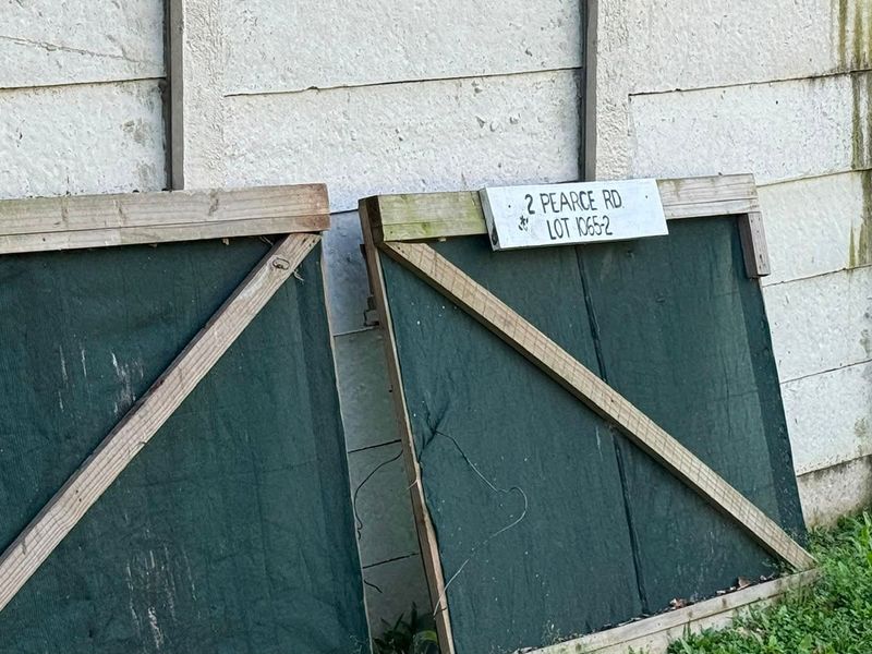 A view of the property boundary wall featuring a site identification sign for 2 Pearce Rd, Lot 1065-2.