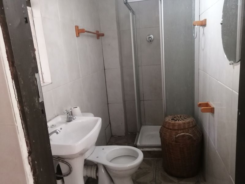 A compact bathroom featuring a pedestal basin, toilet, and a separate shower enclosure with tiled finishes throughout.