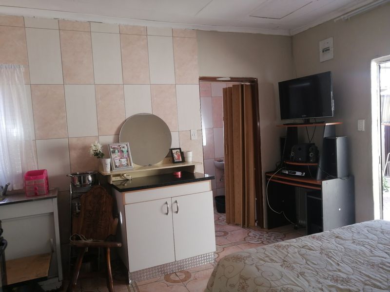 A bedroom featuring tiled wall accents, tiled flooring, and a folding door leading to an adjacent space.