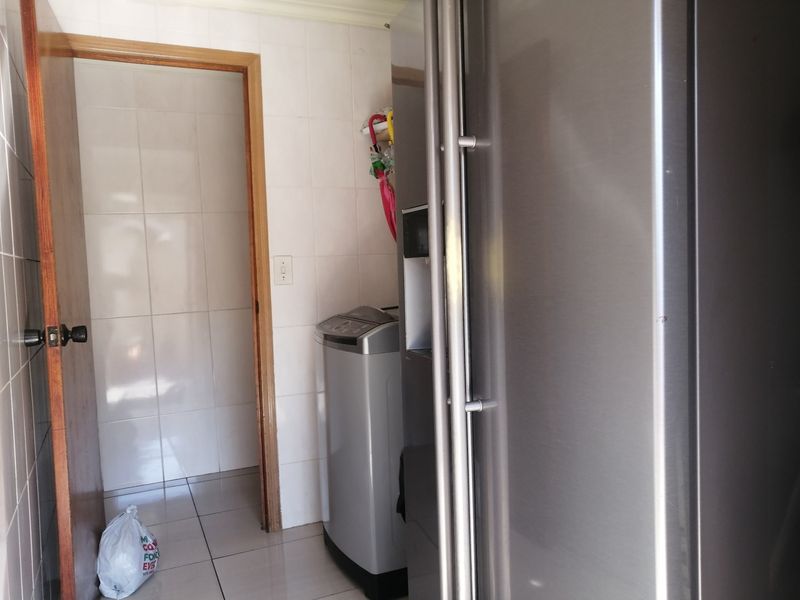 A functional laundry area featuring tiled walls and flooring, providing a clean and practical space for utility tasks.