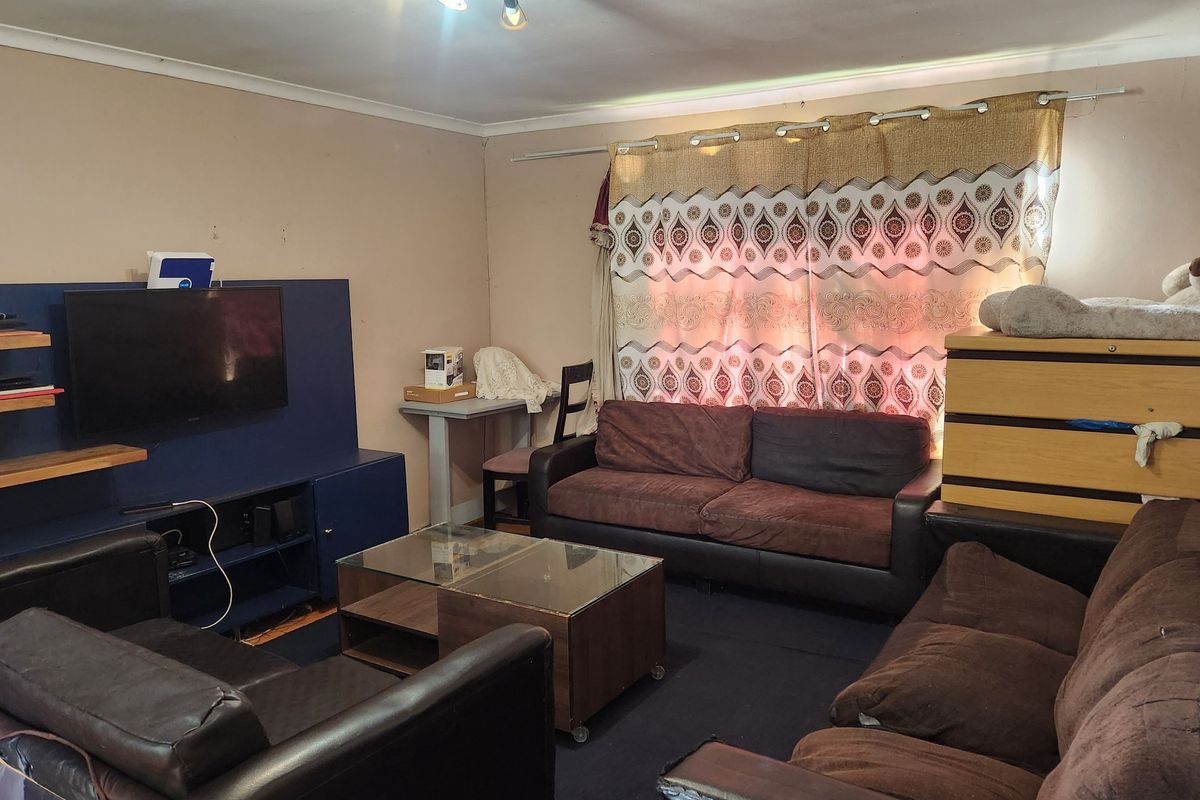 A living room featuring a built-in media unit and ceiling-mounted track lighting, requiring cosmetic updates to the wall finishes.