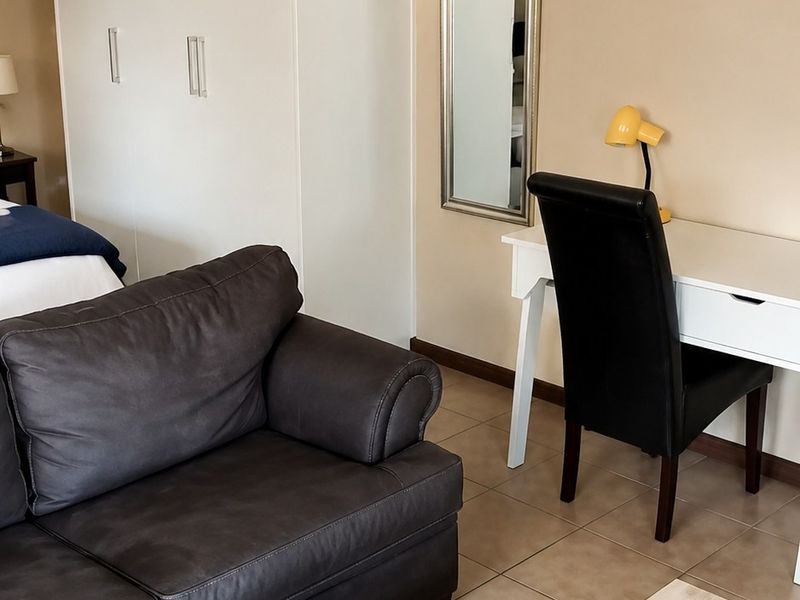 A bedroom featuring tiled flooring, neutral wall tones, and a large built-in wardrobe providing ample storage space.