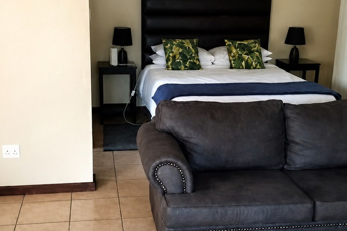 A bedroom featuring tiled flooring and neutral wall finishes, providing a functional space with integrated lighting and coved ceiling detailing.