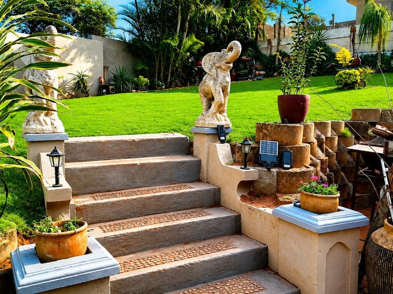 A well-maintained garden featuring concrete stairs with decorative pillars, a retaining wall, and lush green lawn space.