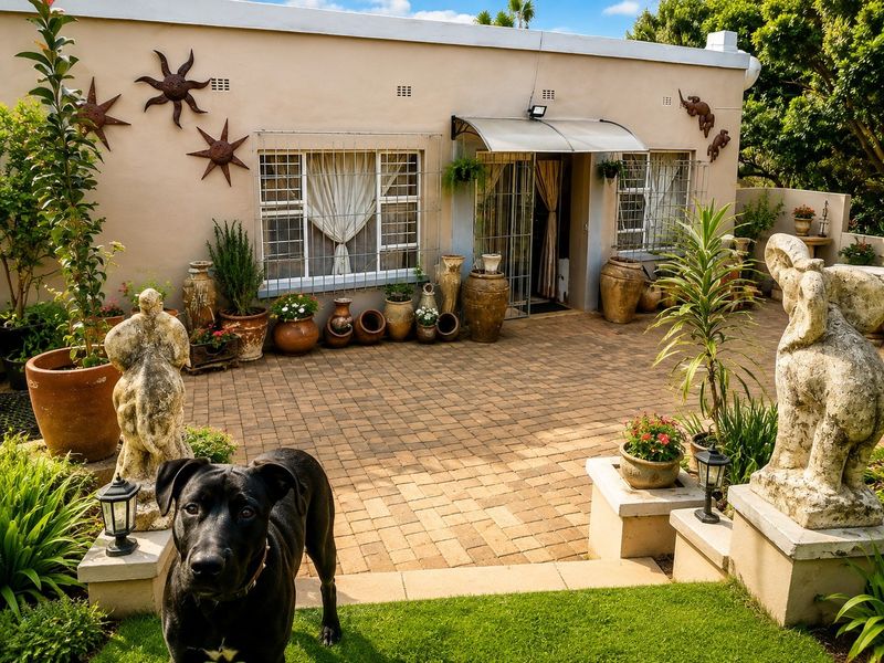 A well-maintained rear paved patio area featuring a brick facade, security-fitted windows, and a protective awning over the entrance.
