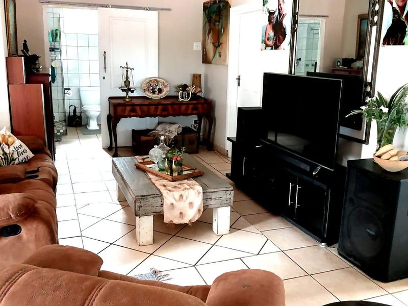 A living room area featuring tiled flooring and a sliding door leading to an adjacent bathroom.