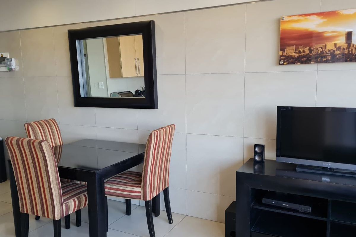 A living area featuring large format wall tiles and a wall-mounted prepaid electricity meter.