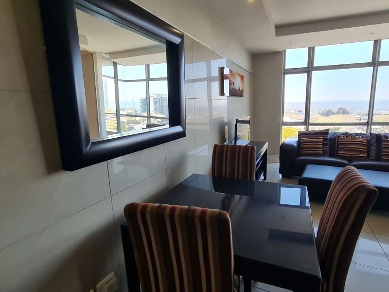 Bright open-plan living and dining area featuring large floor-to-ceiling windows with expansive views and modern tiled finishes.
