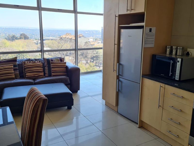 Open-plan living and kitchen area featuring floor-to-ceiling windows with expansive views, tiled flooring, and modern built-in cabinetry.