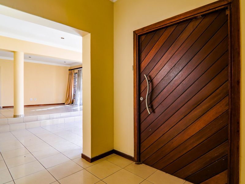 Entrance foyer featuring a solid timber diagonal-plank door, neutral tiled flooring, and an open-plan transition to the main living area.