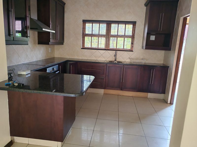 A functional kitchen featuring dark wood cabinetry, granite countertops, a built-in oven, and a tiled backsplash, offering a clean and practical workspace.