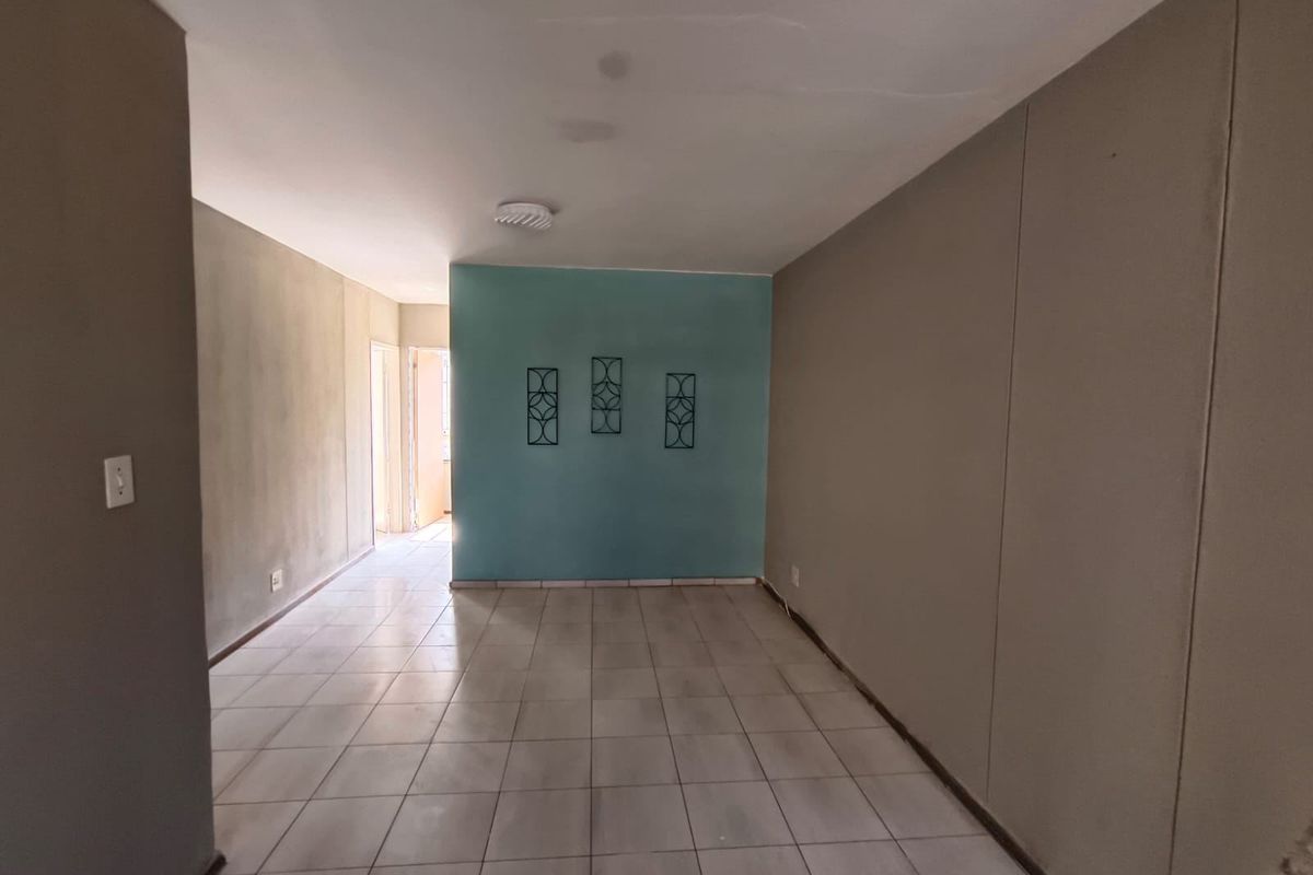An empty living area featuring tiled flooring and a painted accent wall, offering a blank canvas for potential interior design updates.