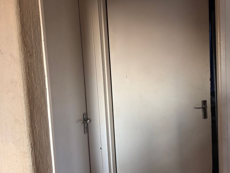 A narrow hallway interior featuring two white internal doors with metal handles and visible wear on the surrounding door frames.