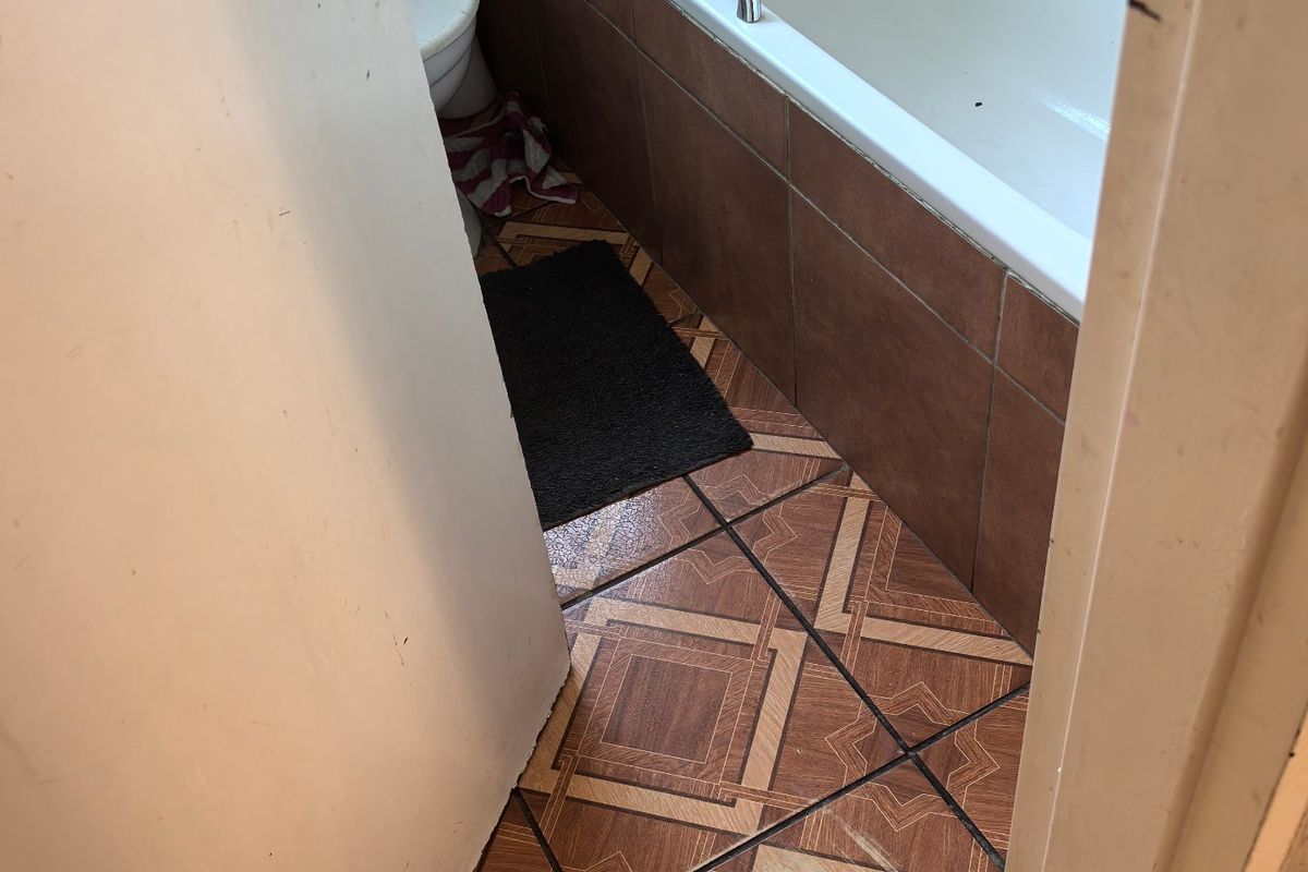 A compact bathroom featuring a bathtub, toilet, and patterned floor tiles. The space is dated and would benefit from modern updates.